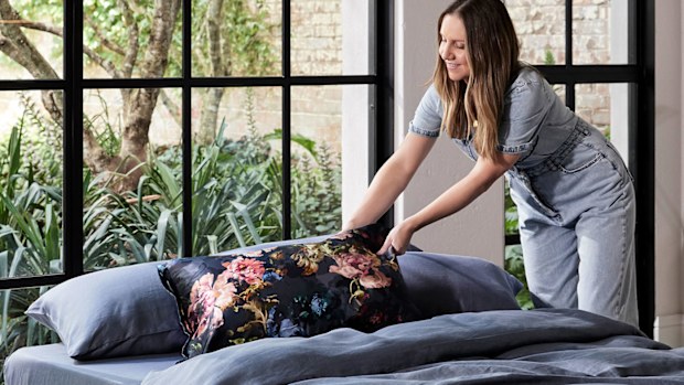 Stylist adds a decorative pillow to a bed