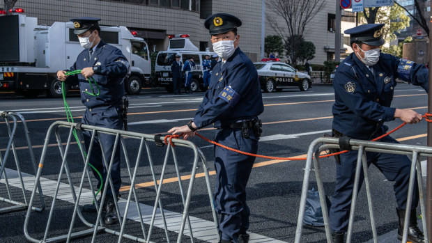  Police officers wearing face masks close a road near the start area of the Tokyo Marathon 