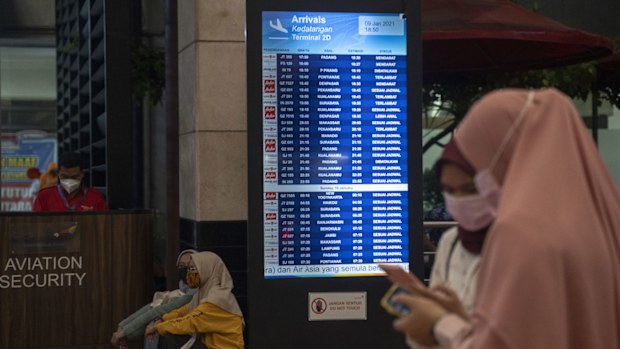 People watch a schedule board at the Crisis centre in Soekarno Hatta Airport, on January 09, 2021 in Jakarta, Indonesia