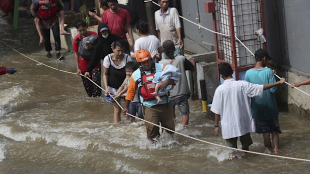 A rescuer, centre, evacuates a baby in flooded neighbourhood in Tanggerang outside Jakarta, Indonesia, Thursday, Jan. 2, 2020.
