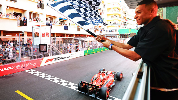 Race winner Charles Leclerc of Monaco driving the (16) Ferrari SF-24 takes the chequered flag waved by Kylian Mbappe during the F1 Grand Prix of Monaco at Circuit de Monaco on May 26, 2024 in Monte-Carlo, Monaco. (Photo by Bryn Lennon - Formula 1/Formula 1 via Getty Images)