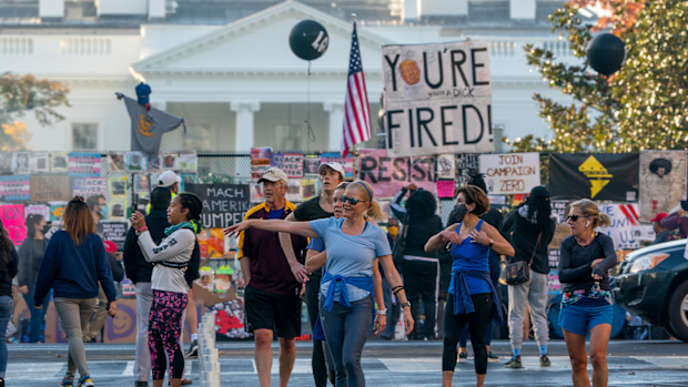 People gather on Black Lives Matter Plaza on the north side of the White House where a tall metal security fence has been covered in protest signs, early Sunday, Nov. 8, 2020. (AP Photo/J. Scott Applewhite)