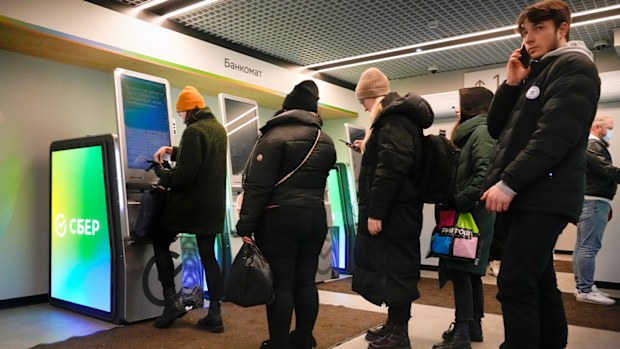 People stand in line to withdraw money from an ATM in Sberbank in St. Petersburg, Russia.