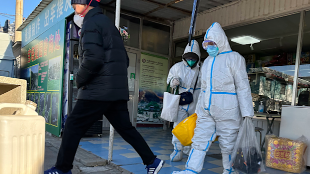 Family members in protective gear collect the cremated remains of their loved one bundled with yellow cloth at a crematorium in Beijing, Saturday, Dec. 17, 2022. 
