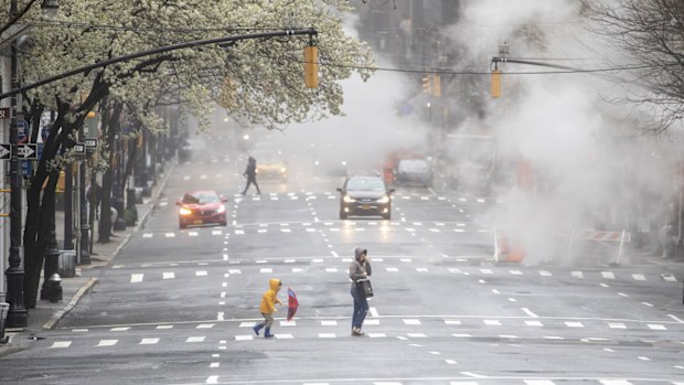 Light traffic frames a woman and child as they walk across Madison Avenue on March 29, 2020, in Midtown Manhattan of New York. 