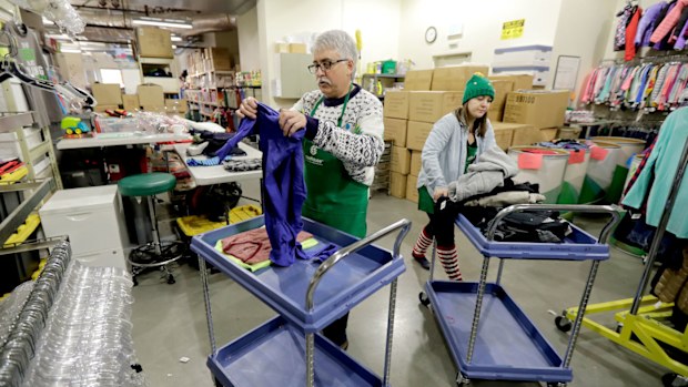 Chris Meyer and Maddi Heim fold and sort donated clothes at Treehouse, a nonprofit organisation in Seattle that is one of several charities that received donations from the $11 million secret estate of Alan Naiman.
