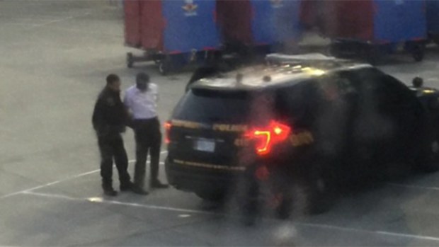 The co-pilot is led away in handcuffs. (Amanda Albrecht / Twitter)
