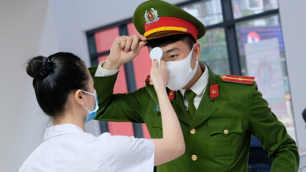 An official receives temperature check on arrival at the stadium prior to the Women's Olympic Football Tournament Play-Off 2nd Leg between Vietnam and Australia