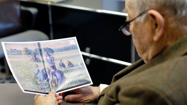 Jean Jacques Bauer, looks at a reproduction of a valuable Camille Pissarro painting he recovered. (Photo: AP).