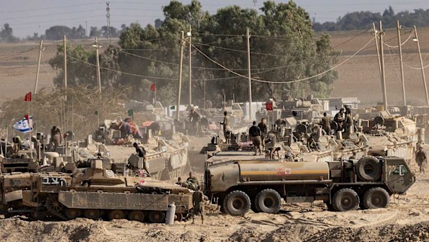  Israeli soldiers organise military equipment while standing on armored personnel carriers near the border with the Gaza Strip.