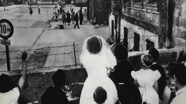 The Berlin Wall was hastily constructed and separated families. Here a bride and groom wave to loved ones on the other side of the Wall.