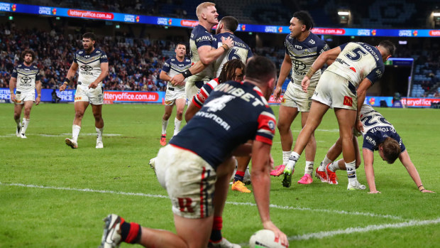 The Cowboys celebrate after tackling Roosters gun Joey Manu into touch.