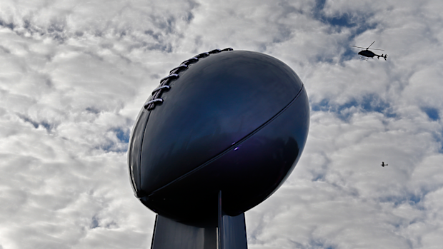 A helicopter and small plane fly overhead a large Super Bowl trophy at NFL Live in Atlanta, Georgia.