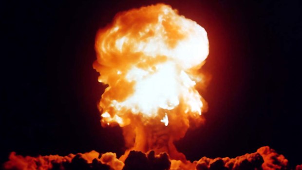 A nuclear explosion sends a mushroom cloud up into the sky.