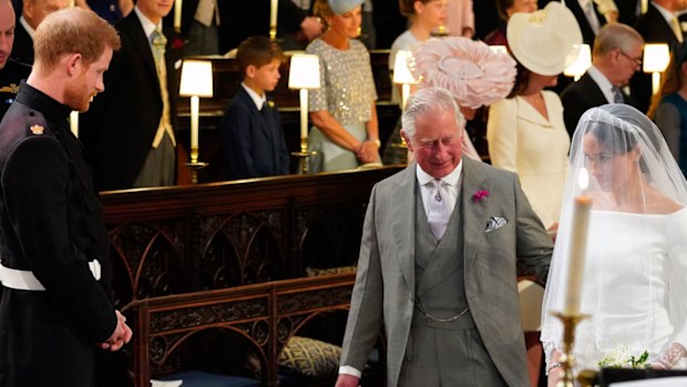 Britain's Prince Harry looks at his bride, Meghan Markle, as she arrives accompanied by the Prince Charles during the wedding ceremony of Prince Harry and Meghan Markle at St. George's Chapel in Windsor Castle in Windsor, near London, England, Saturday, May 19, 2018