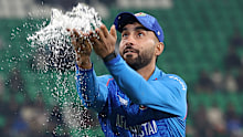 LAHORE, PAKISTAN - FEBRUARY 28: Afghanistan captain Hashmatullah Shahidi picks up water from the outfield after rain stopped play during the ICC Champions Trophy 2025 group match between Afghanistan and Australia at Gaddafi Stadium on February 28, 2025 in Lahore, Pakistan. (Photo by Matthew Lewis-ICC/ICC via Getty Images)