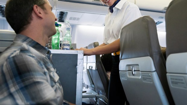 Portrait of a friendly flight attendant serving food and drinks in an airplane and looking happy - travel concepts