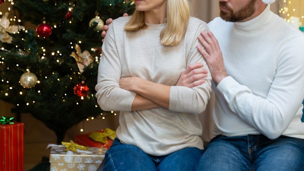 A husband calms his wife and tries to make peace, a quarreling couple sits on the sofa at home near the Christmas tree, a shot of the family celebrating the New Year.