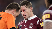 Harry Grant of the Maroons is attended to by a trainer after copping a knock to the face.