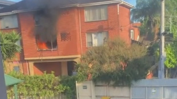 A man has been saved by his neighbours after they saw him hanging from the window of his burning apartment in Melbourne.