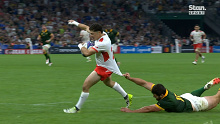 A South African player tries valiantly to stop Patrick Pellegrini from scoring Tonga's final try of the match.