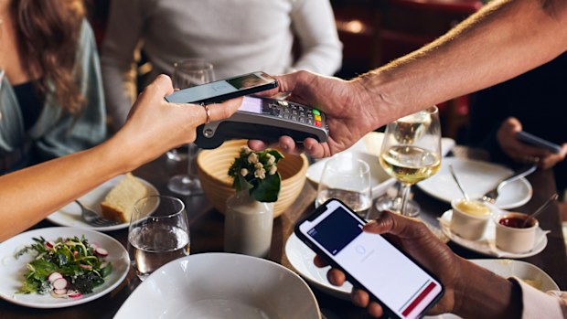 Friends paying contactlessly in restaurant