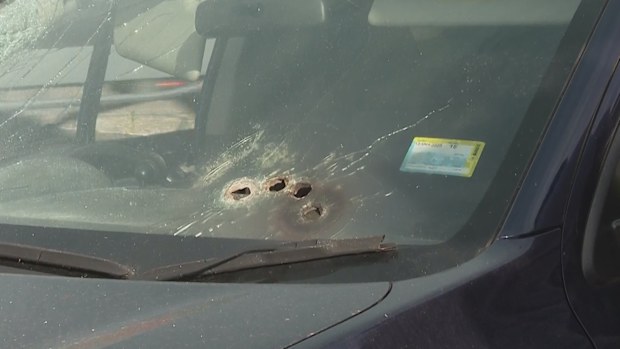 A car with multiple bullet holes in the windshield.