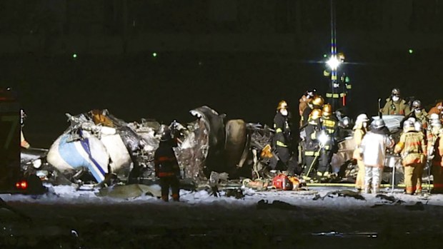 Firefighters are seen near the part of the burnt Japanese Coast Guard aircraft on the runway of Haneda airport on Tuesday, Jan. 2, 2024 in Tokyo, Japan. A passenger plane collided with the Japanese coast guard aircraft and burst into flames at the airport on Tuesday, officials said. (Kyodo News via AP)