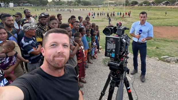 Nine camera operator Shaun Welfare takes a snap of 9News reporter Zac Bailey in Port Moresby surrounded by league loving PNG citizens.