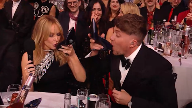 Kylie Minogue and Roman Kemp do a shoey during the 2024 Brit Awards