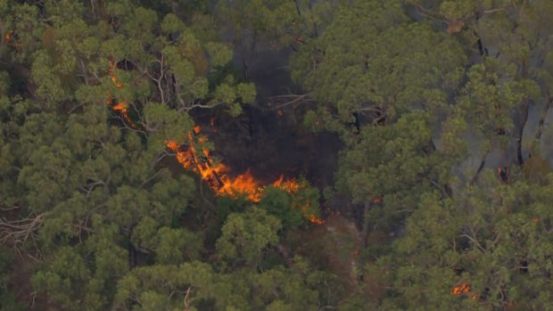 An out-of-control bushfire is burning dangerously close to homes in Melbourne's east as erratic winds and heatwave conditions are felt across the city.