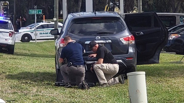 Law enforcement officials take cover outside a SunTrust Bank branch
