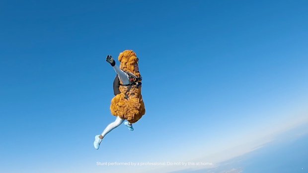 KFC's human drumstick skydives down towards a giant delivery bag. 