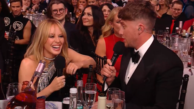 Kylie Minogue and Roman Kemp do a shoey during the 2024 Brit Awards