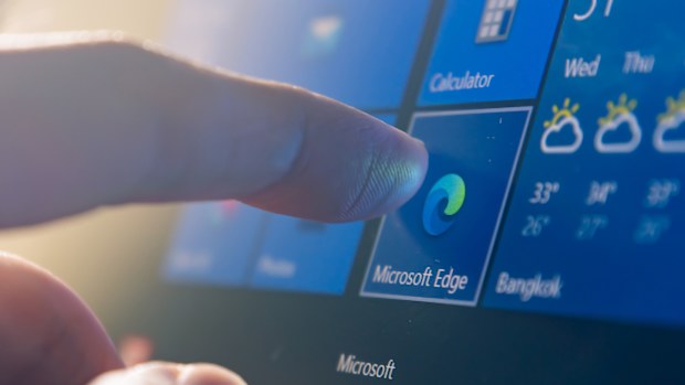 Computer user touching on Microsoft Edge, a web browser developed by Microsoft, icon on Windows 10 to open the program.