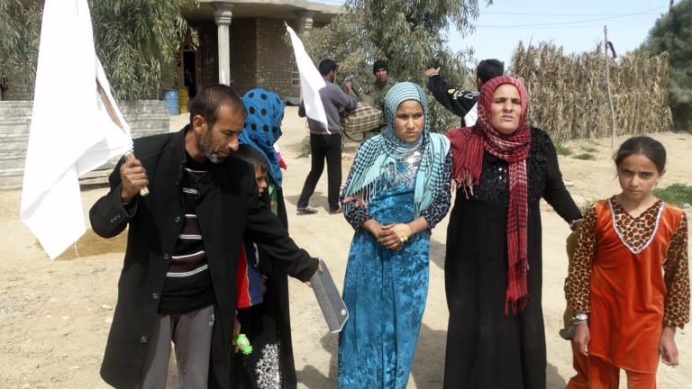 Civilians hold white flags as they emerge from their houses after clashes between Iraqi security forces and IS terrorists near Ramadi on Wednesday.