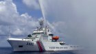 A Chinese Coast Guard boat sprays a water cannon at Filipino fishermen.