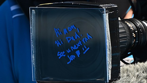 Jessica Pegula signs a message to her parents after winning her fourth round Australian Open match.