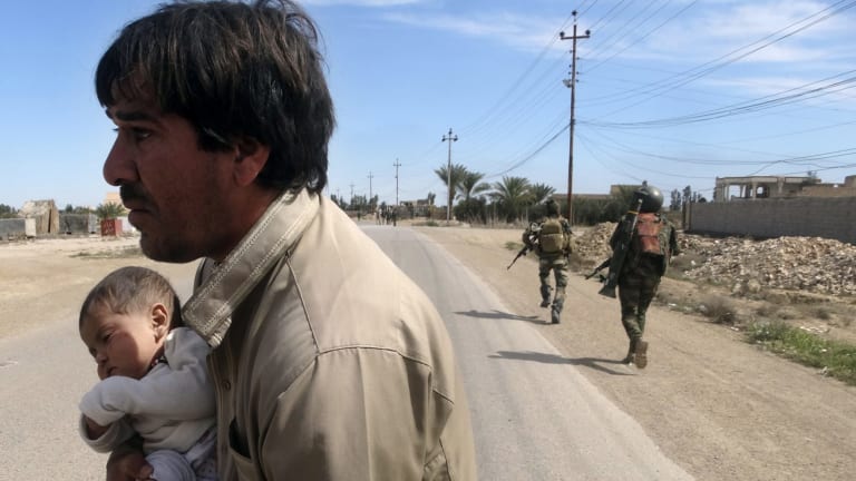 A man and baby flee after clashes between IS and Iraqi Security forces at a village outside Ramadi on Wednesday.