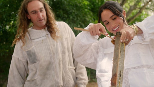Meghan is pictured scraping honey off hive frames with beekeeper Branden Aroyan.**This image is for use with this specific article only** 