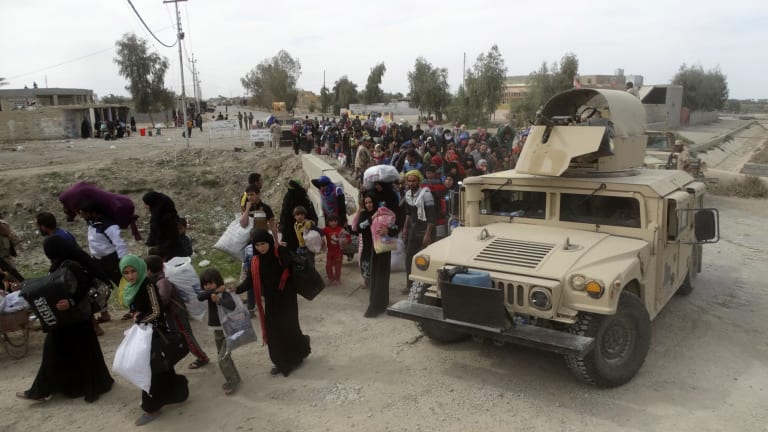 Iraqi soldiers help civilians flee their village outside Ramadi after clashes with IS on Wednesday.