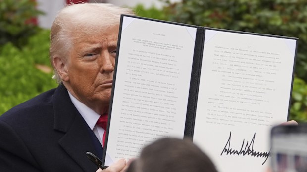 President Donald Trump holds a signed executive order during an event to announce new tariffs