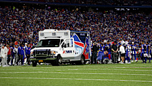 Players from both teams gather on the field as an ambulance takes Dane Jackson away. 