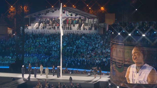 Luan Pommier sings as the Paralympic flag is raised.