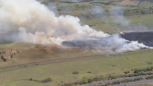 A large grassfire is burning on the edge of Sydney, with residents warned to stay updated.The fire has burned through bush around Menangle Road, near Menangle in Wollondilly, with waterbombing aircraft called in.