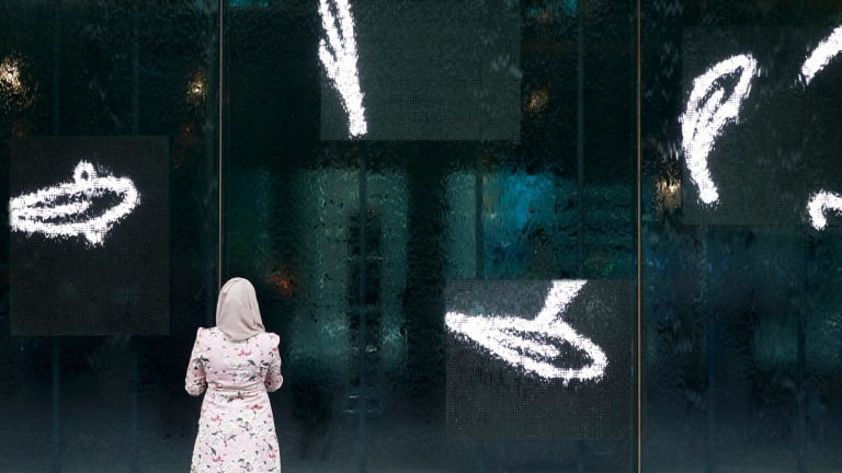 A visitor watches fish swimming at the waterwall entrance to NGV International.