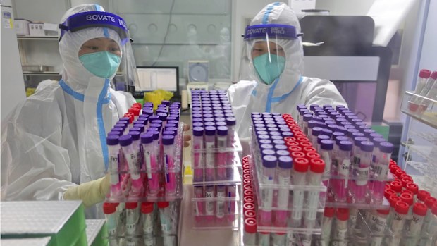 Workers handle swab samples for COVID-19 tests at a hospital lab in Yantai