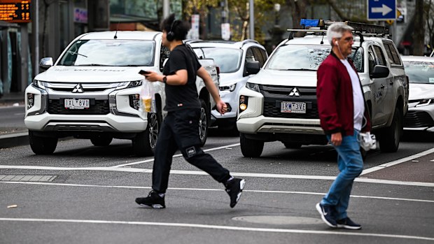 Pedestrians walk past dual-cab utes.