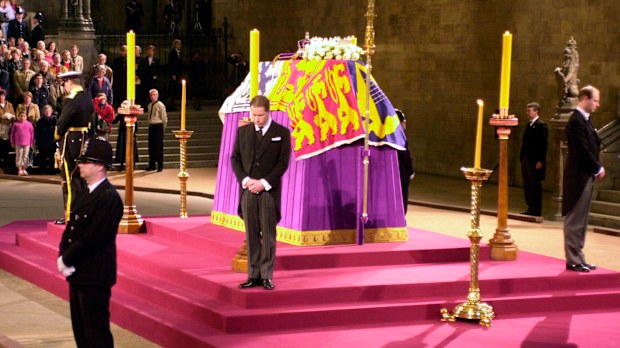 FILE - The flag-draped coffin of Queen Elizabeth the Queen Mother Lies-in-State, as it is guarded at the four corners of the catafalque by her four grandsons: the Duke of York, left, the Earl of Wessex, right, Viscoount Linley, center, and the Prince of Wales, hidden - far side, in Westminster Hall London on the eve of her funeral, Monday, April 8, 2002.  When Queen Elizabeth IIs grandfather, King George V, died in 1936, life in Britain is unrecognizable to people today. But despite almost a ce