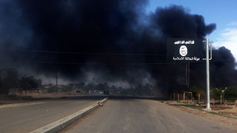 Smoke billows behind an Islamic State street sign during clashes between the terrorist group and Iraqi security forces in Sadiyah, north of Baghdad, in 2014.